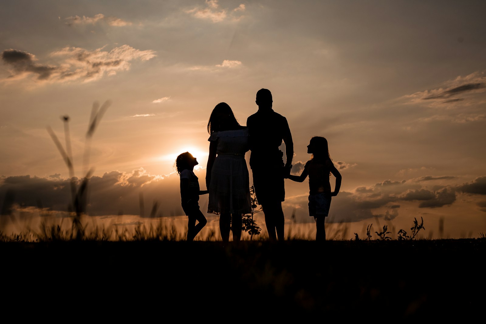 A family standing together in an open field at sunset, in golden light.